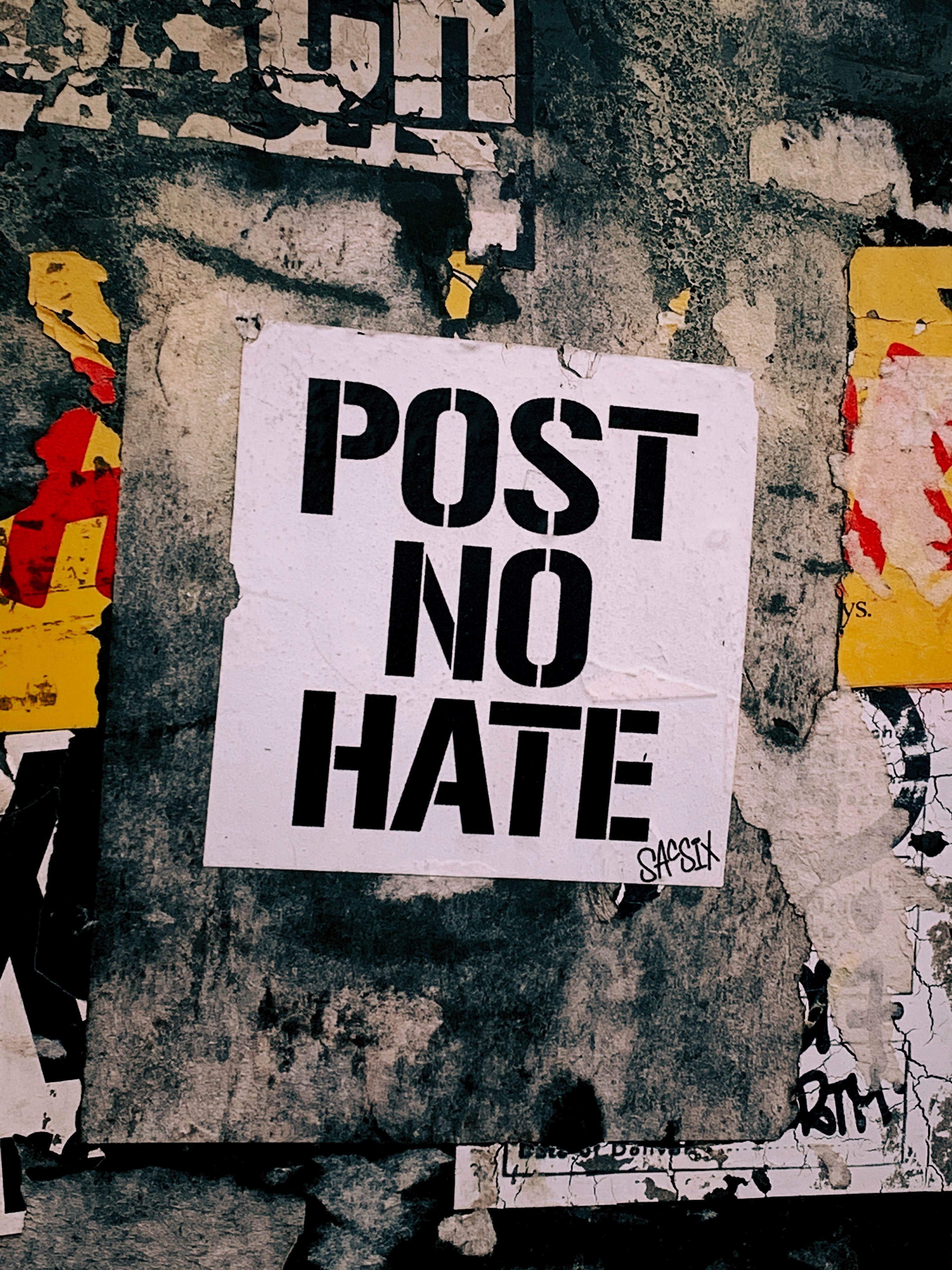A white placard stating post no hate
