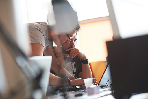 A photograph of two people looking at a laptop.