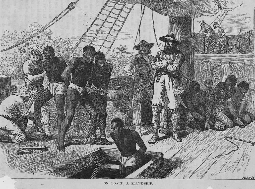 A wooden engraving, circa 1835, showing slaves on a slave ship being shackled before going into the hold.