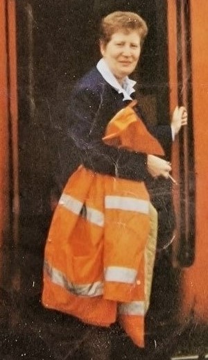 Janet cassidy in her early years as a train driver, standing in work clothes in the entrance to the train