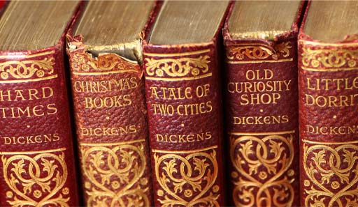 This is a colour photograph of five books bound in red leather. Their titles are tooled in gold on the spines, and include Hard Times, A Tale of Two Cities, and Little Dorrit.