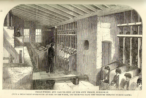 This is a black and white illustration of prisoners at work under supervision in a low-ceilinged room. Along the right-hand wall is a rank of numbered cubicles, in which men are operating treadmills. Other prisoners are lined up in box-like seats, plucking at the fibre on their knees.