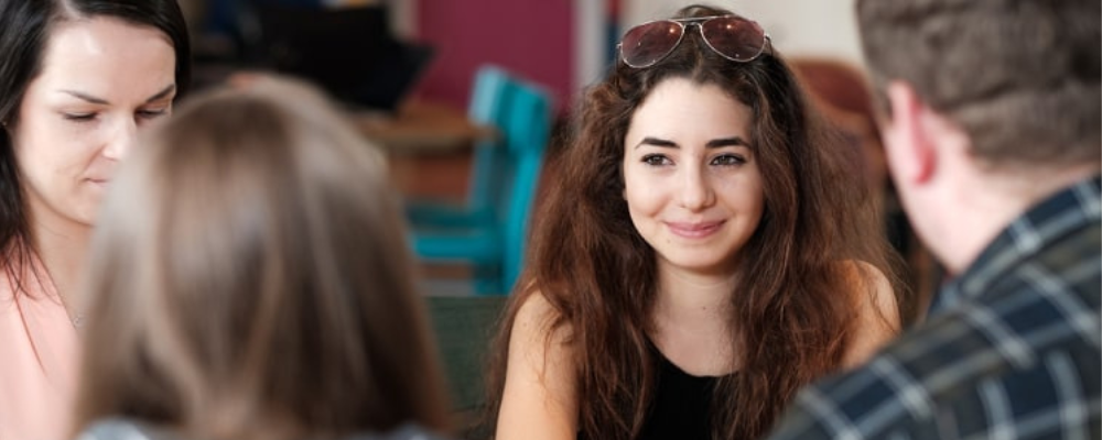 Female student sitting at table with friends