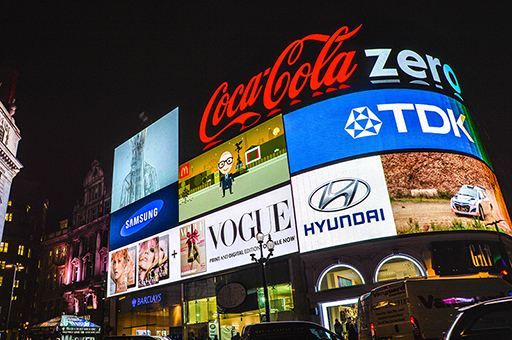 Photograph of a building in a busy city with multiple digital billboards.