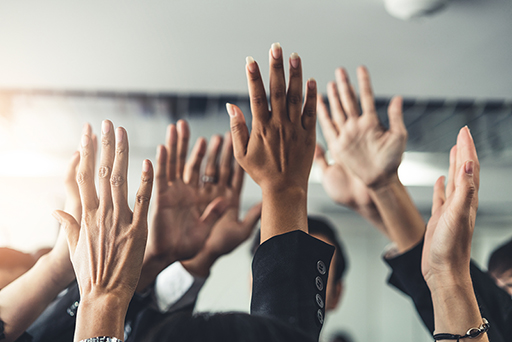 Photograph of multiple hands in the air.