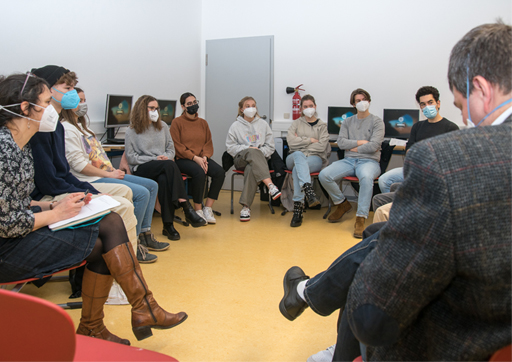 A group of young people sat on chairs in a circle with a teacher.