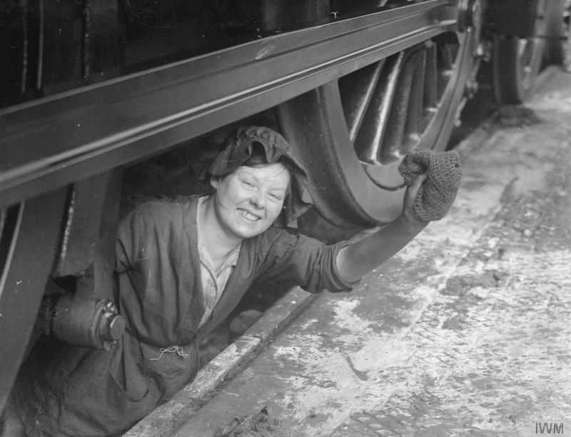 Woman working in the locomotive cleaning pit, looking out smiling