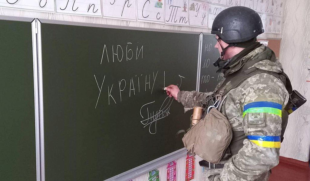 Ukraine border guard writing 'I love Ukraine' on a blackboard