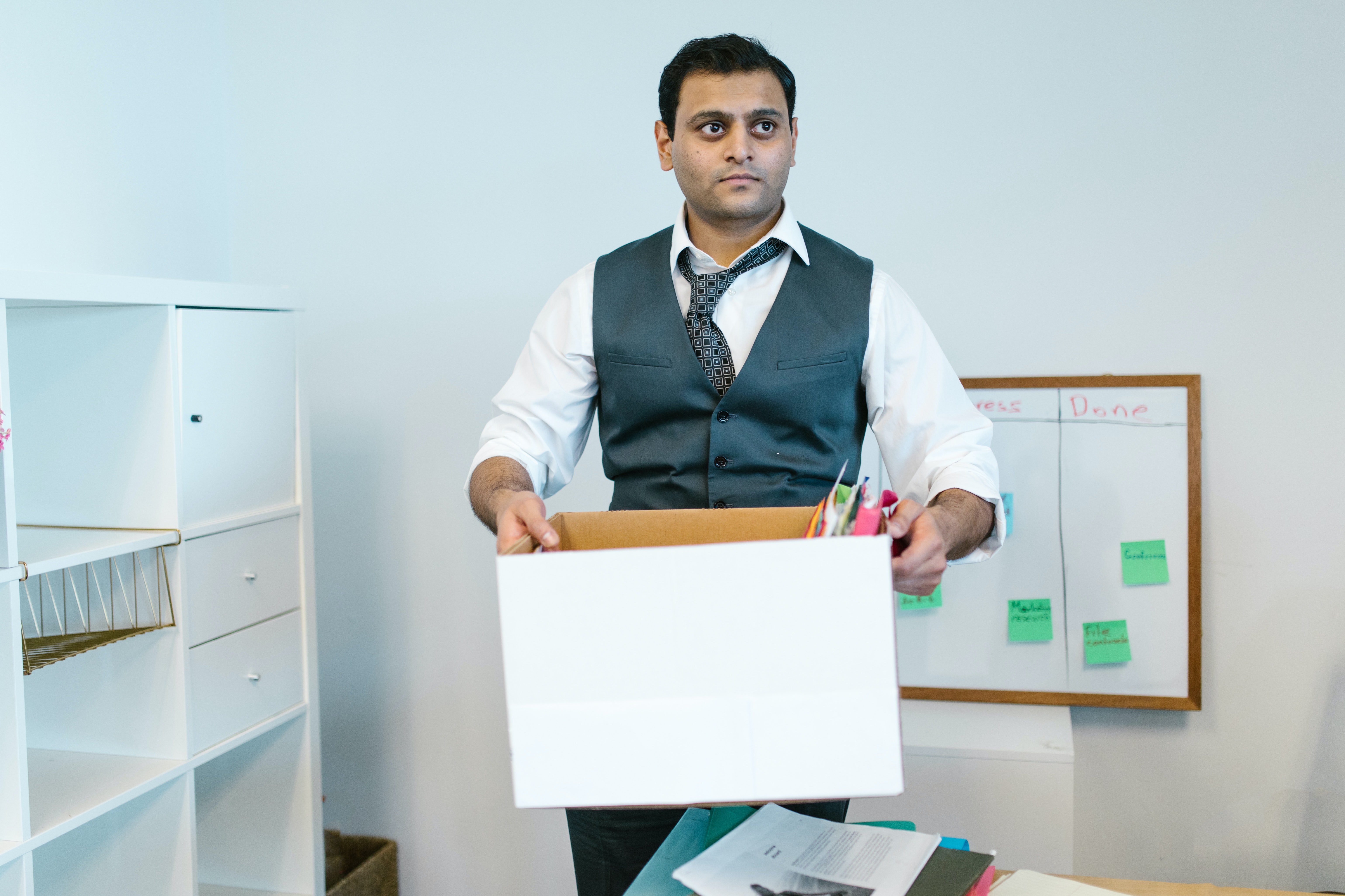 An employee by his desk, holding a half-filled packing box.