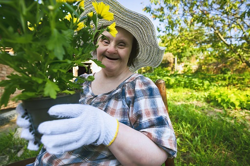 An image of a woman outside in a garden holding a plant.