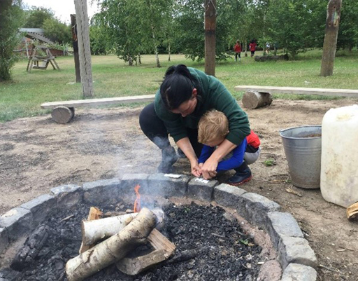 A toddler being supervised while exploring a fire pit.