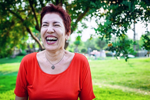 A photograph of a smiling woman outdoors.