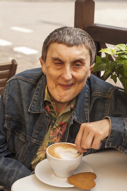 A photograph of a man smiling, with a hot drink.