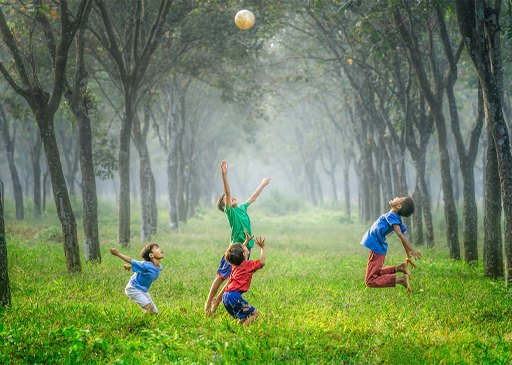 An image of four children jumping up and down in a green space