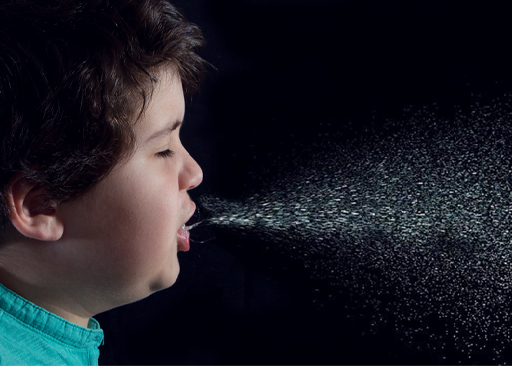 A photograph of a child sneezing, with visible germs leaving their mouth