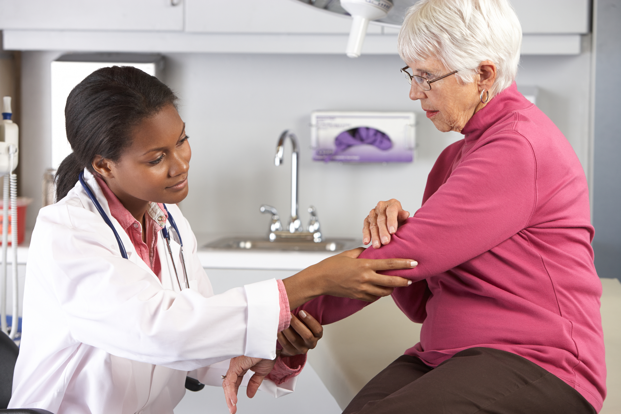 Doctor examines and elderly patient with elbow pain