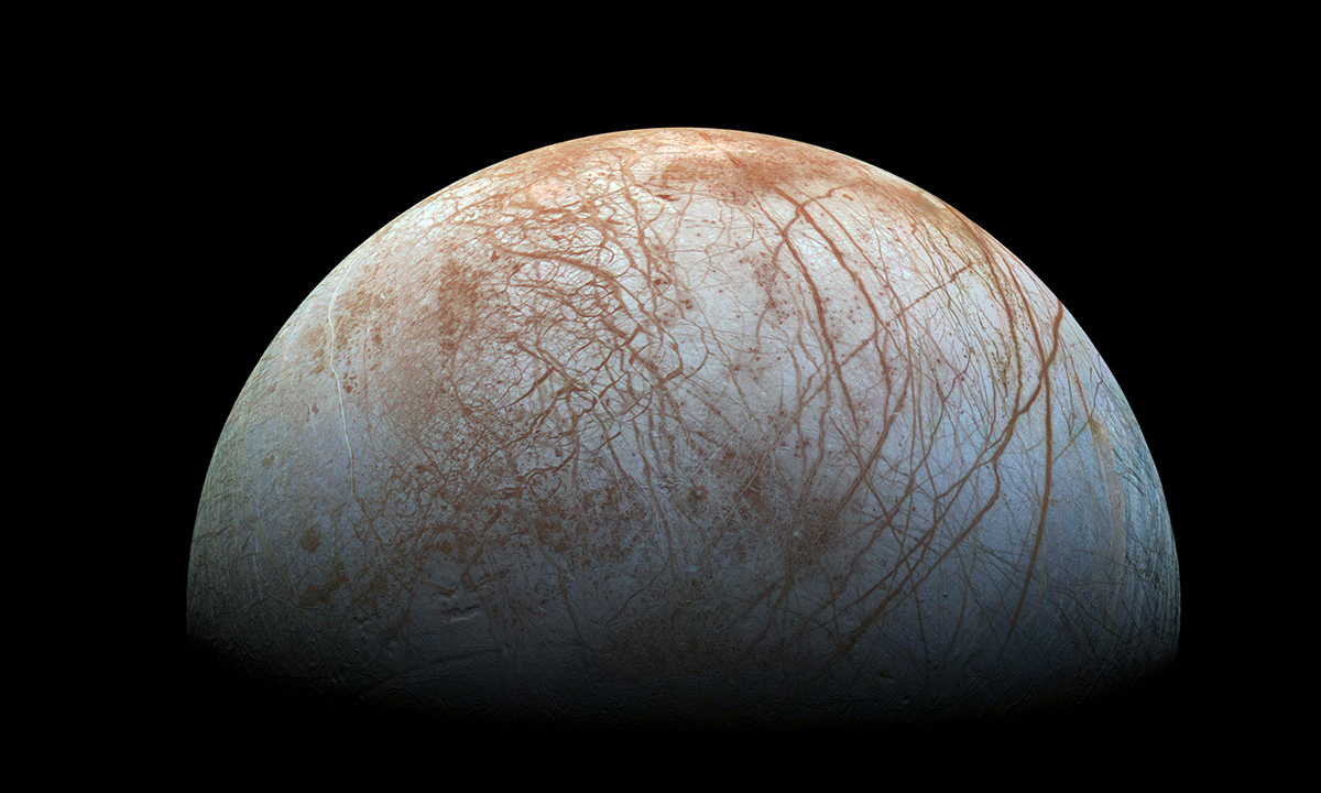 Photograph of the surface of Europa. The grey-blue icy surface is criss-crossed with reddish cracks where the ice shell has b
