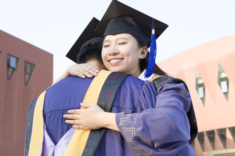 two graduates hugging