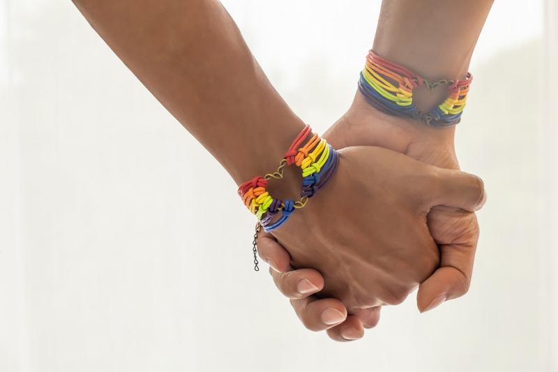 Asian male couple holdings hands with the pride wristbands
