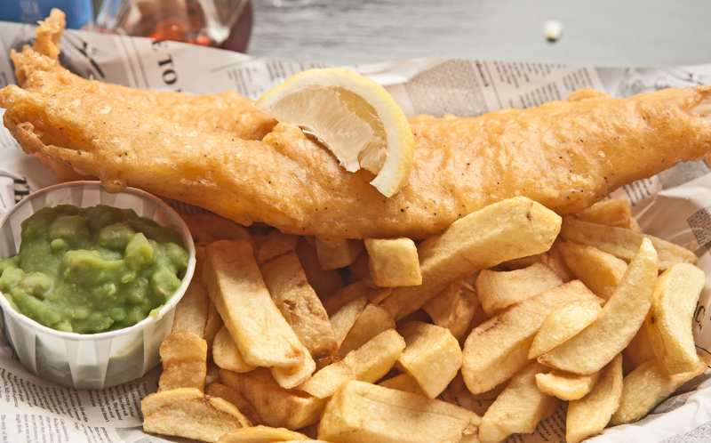 Fish, chips, mushy peas and a slice of lemon, wrapped in newspaper