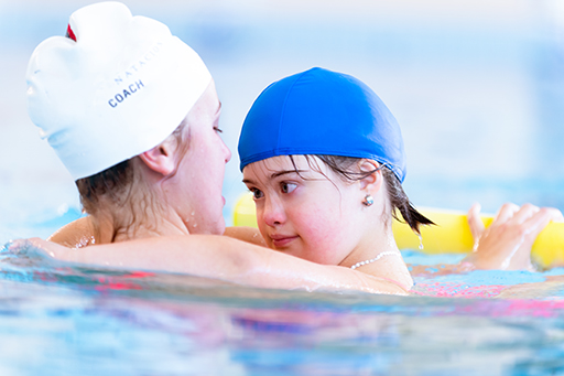 A child being supported in a swimming pool by an adult