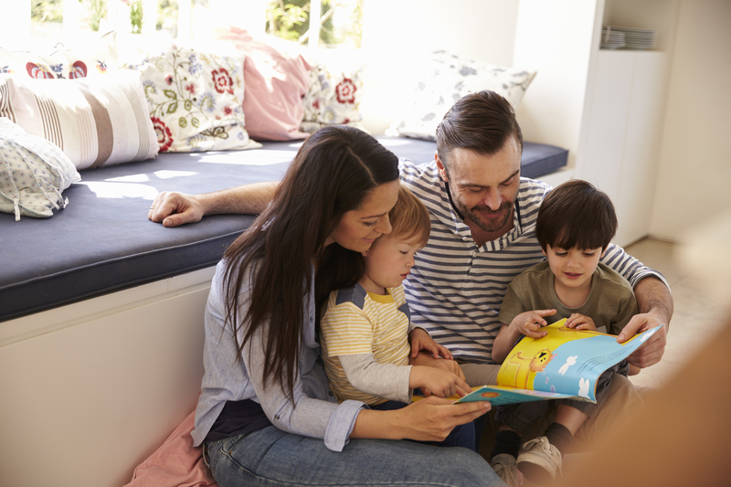 Family Sitting On Floor Reading Story At Home Together