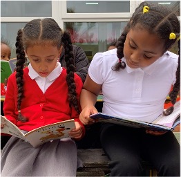 Photo of two children reading next to each other.