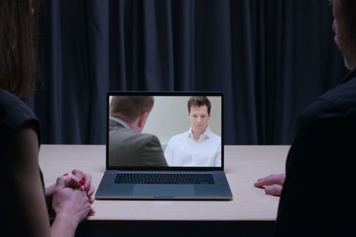 A photograph of an interview between DI Bullet and Neale Anderson being watched from a laptop.