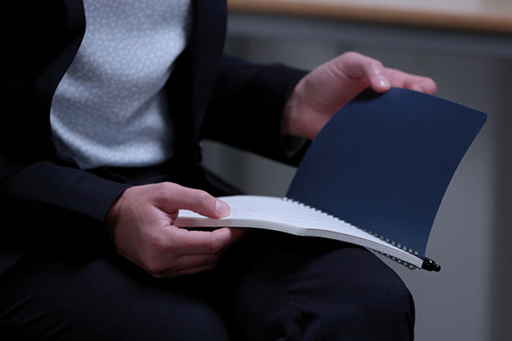 A close up a person’s hands holding an open notebook.