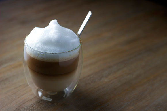 A cup of caffè latte with milk foam.
