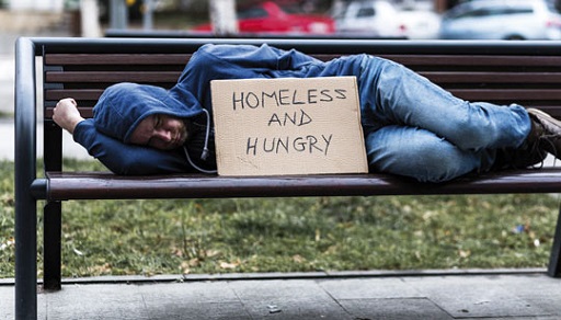 Photograph of a homeless young man sleeping on a park bench.