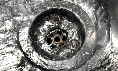 Photo of a sink plug hole with water swirling down it.