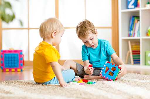 Two young children playing together with a shape sorter