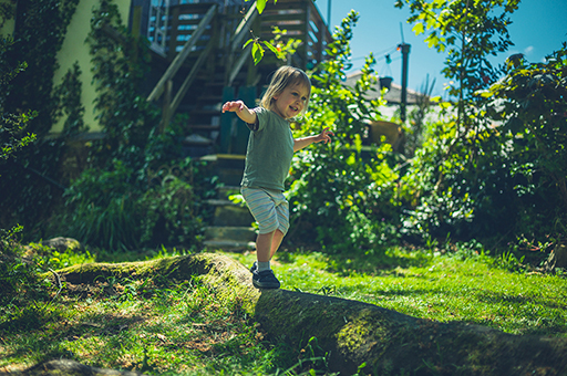 A young child walking along a narrow mound