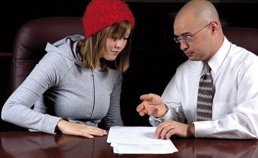 Photograph of a young woman going through documents with her legal adviser.