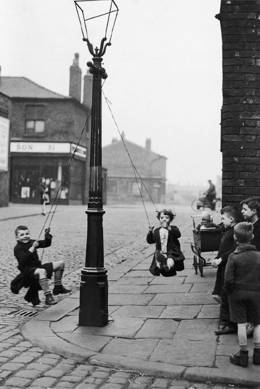 A black-and-white photograph of children playing in the street
