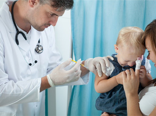 A photograph of a child with its parents, receiving an injection from a healthcare worker