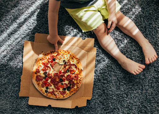 A photograph of a child sat with a pizza.