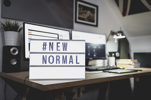 Desk with the sign #New Normal on it.