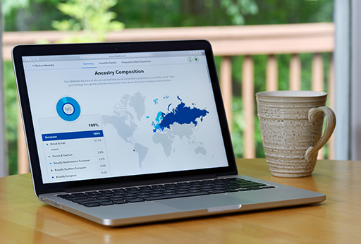 A laptop on a table. On the screen is an ‘Ancestry Composition’ website.