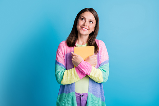 A person holding a book to their chest and smiling.