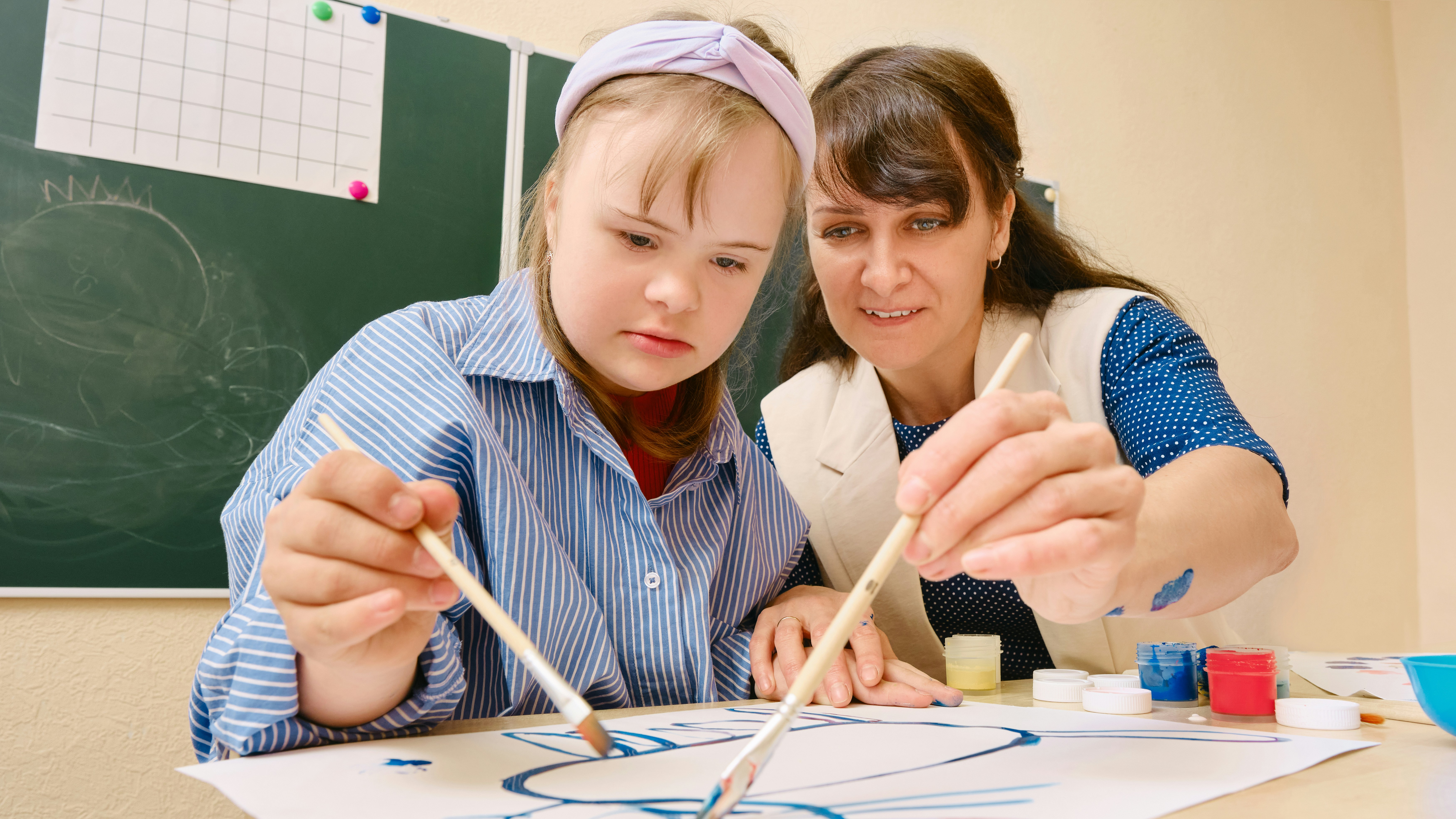 Art therapy lesson between young student with Downs Syndrome and a teacher