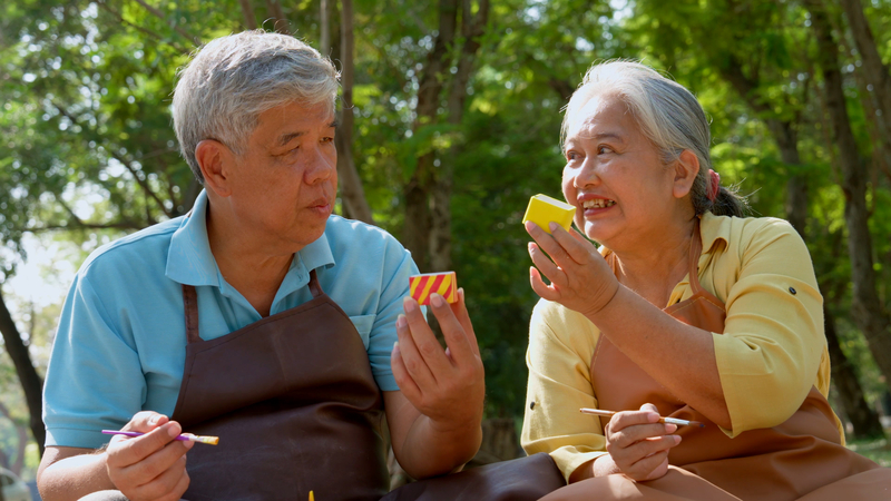 Elderly Asian people painting cactus pots for outdoor art therapy 
