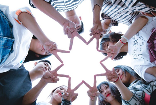 A group of people standing in a circle, with their fingers interlinked.