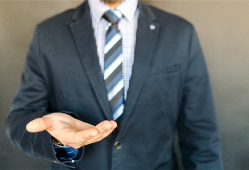 A suited man holding out his hand.