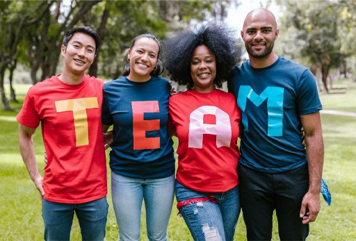 Four people with letters on their clothing spelling out the word ‘TEAM’.