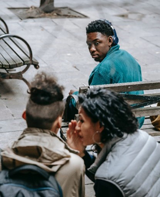 Two people whispering to each other while another person looks on.
