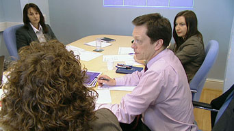 A photograph of four people sitting round a table in a meeting room.