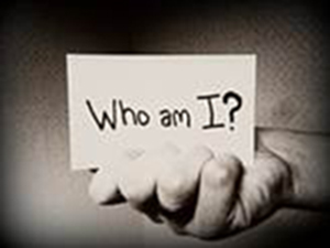 Photo of a hand holding a card with 'Who am I?' written on it.