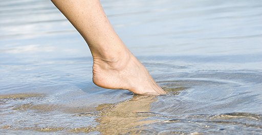 Photo of a toes being dipped into the sea.